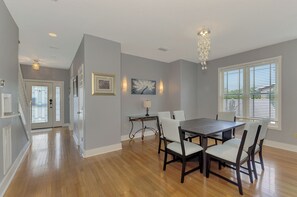 A dining area with a table and chairs, a chandelier, and artwork on the walls. - Magnolia House Sarasota (Sarasota)