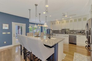 A modern kitchen with granite countertops, stainless steel appliances, and pendant lighting. - Magnolia House Sarasota (Sarasota)