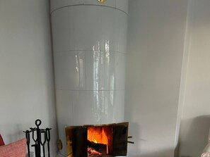 A room with a fireplace, a black metal stand, and a white wall. - Holiday Home Hochstieg 30 (Nieblum)