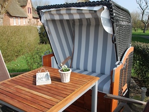 A wooden deck with a striped outdoor chair and a small table. - Holiday Apartment in Wrixum With Terrace (Wrixum)