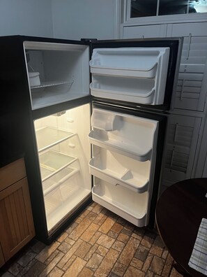 Un refrigerador abierto con múltiples estantes y un compartimento congelador.