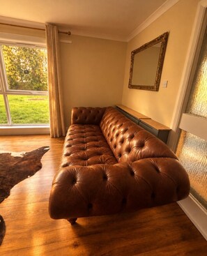 Ein modernes Wohnzimmer mit einem großen braunen Ledersofa, einer Holzbank und einem großen Spiegel an der Wand.