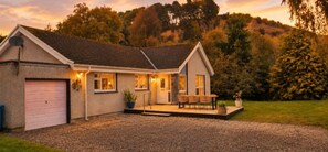 Ein zweistöckiges Haus mit Garage, einer überdachten Veranda mit Stühlen und einem Schotterweg.