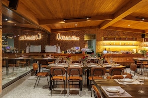 Een restaurantinterieur met houten wanden, een bar en gedekte tafels.