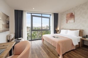 Een hotelkamer met een groot raam, een bed, een bureau en een stoel.
