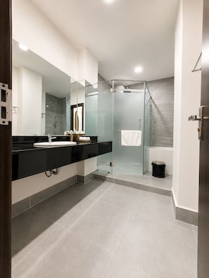 Een moderne badkamer met een douchecabine van glas, een grote spiegel en een zwart aanrecht.