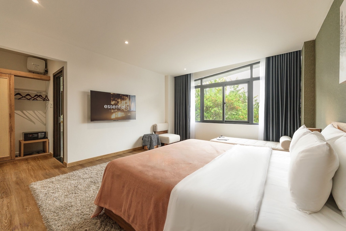 Een moderne hotelkamer met een groot bed, een flatscreen televisie, een kledingkast en een raam met gordijnen.
