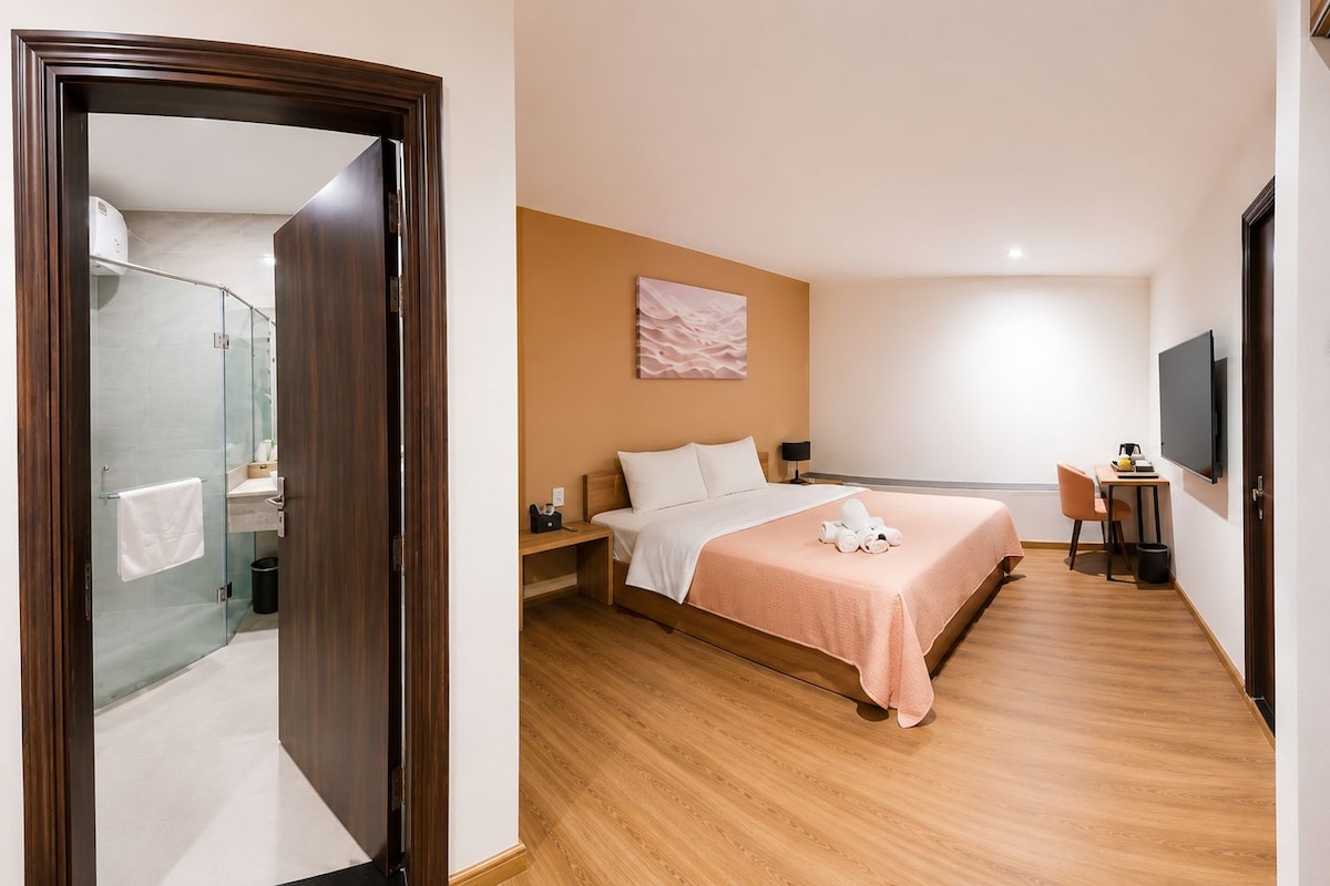 Een hotelkamer met een bed, nachtkastje, stoel, televisie en een douchehoek.