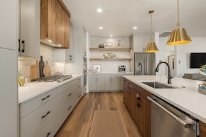 A modern kitchen with a central island, stainless steel appliances, and wooden cabinetry. - The Desert Isle: Private Hot Tub + Family Games (Washington)