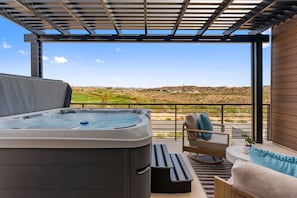 A hot tub on a balcony with a view of a golf course and distant buildings. - The Desert Isle: Private Hot Tub + Family Games (Washington)
