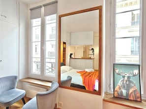 Habitació d'hotel amb un mirall gran, un llit amb capçalera blanca, una taula i una cadira.