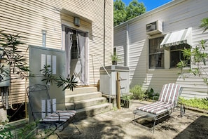 A residential property with a covered patio area featuring two metal chairs with striped cushions, a small step leading to the entrance, and a metal utility box. - Walk to Shops & Restaurants! Classic Nola Home (New Orleans)