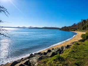 A coastal scene with a clear sky, a sandy beach, and a bridge in the distance. - Forth Bridge View | Private Balcony | Waterfront | Near Edinburgh | Near Airport (Dalgety Bay)