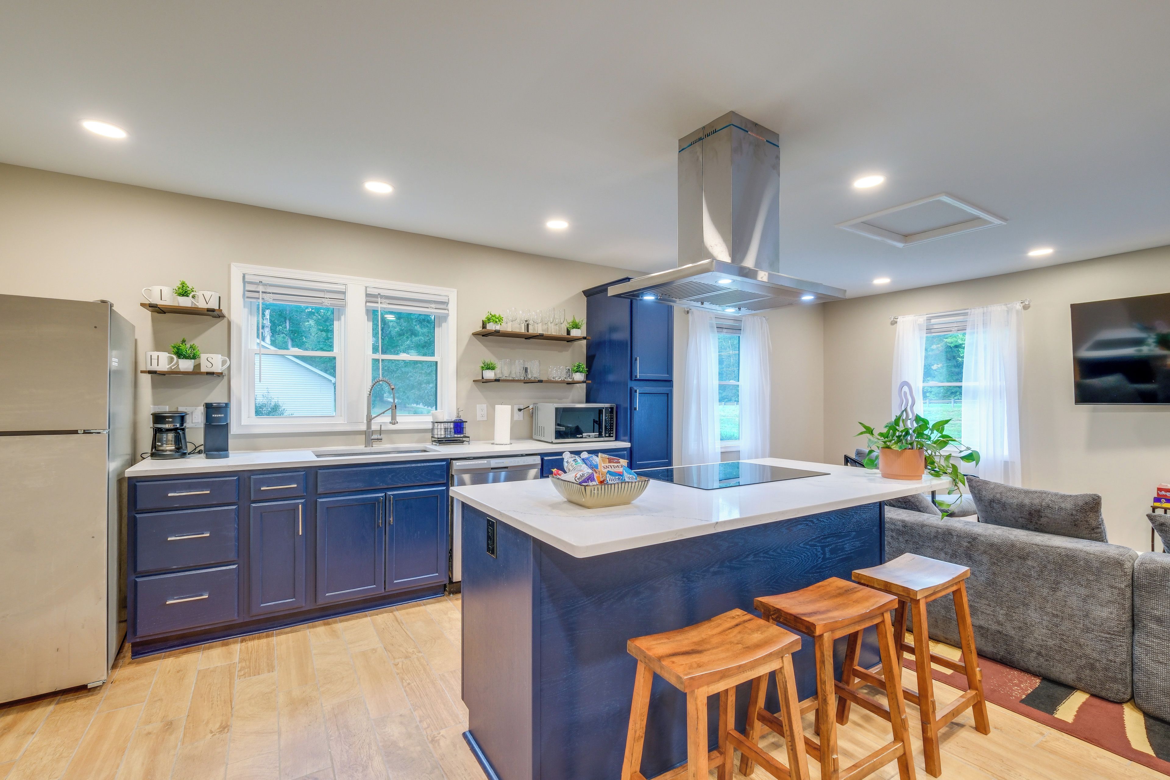A modern kitchen with a central island, bar stools, and a built-in oven.
