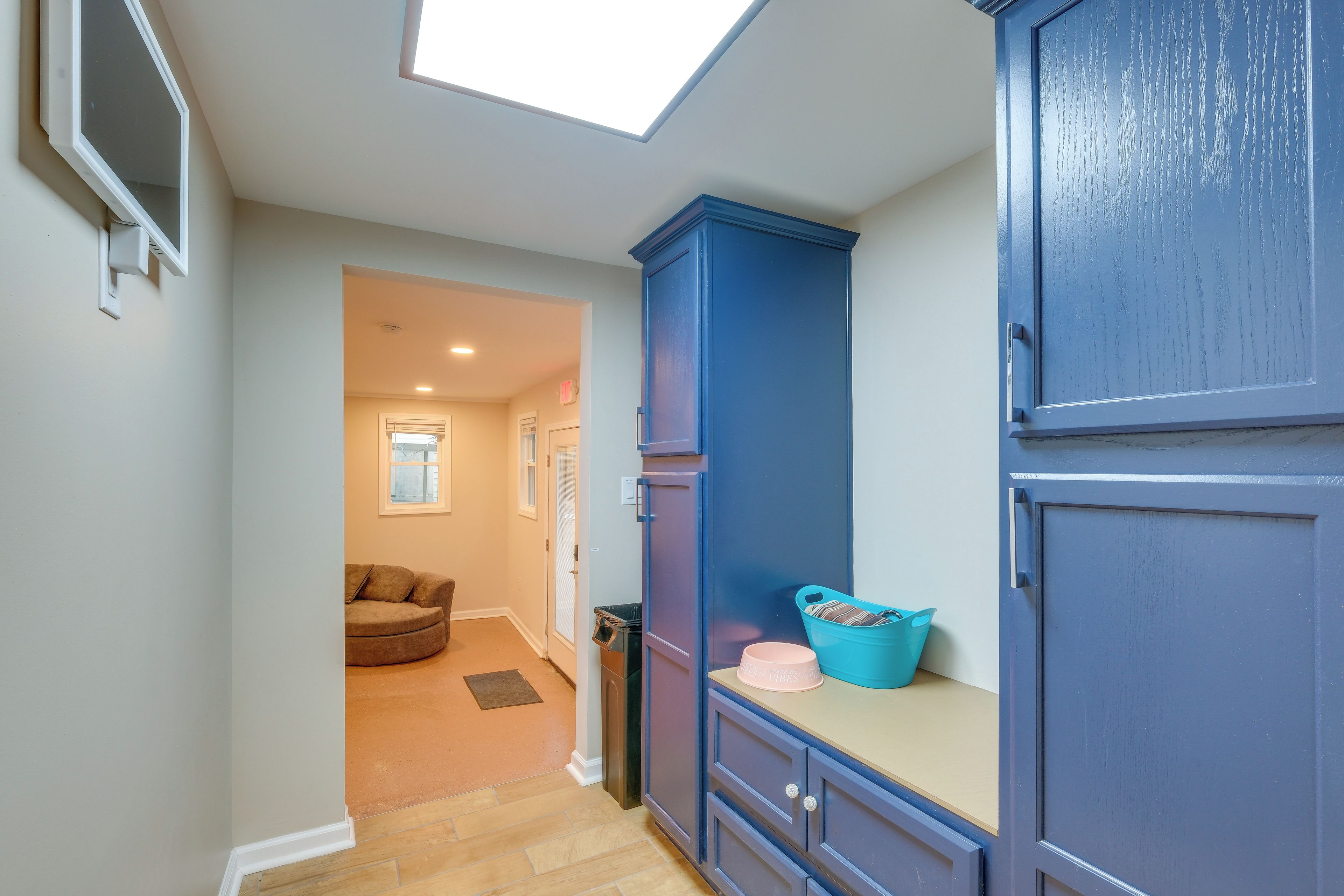 A hallway with a skylight, a blue cabinet, and a door leading to another room.