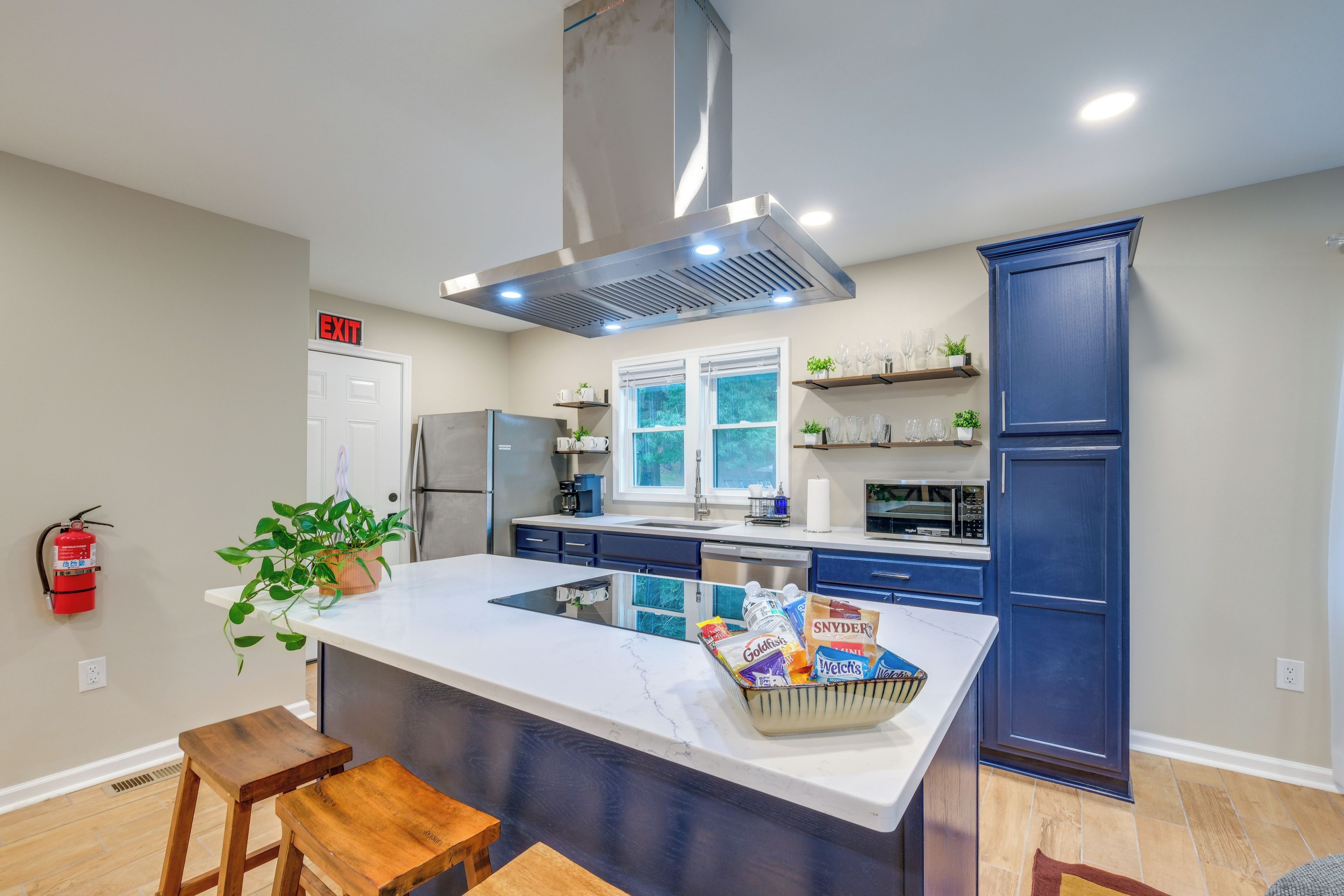 Una cocina moderna con una isla central, electrodomésticos integrados y un ventanal grande.