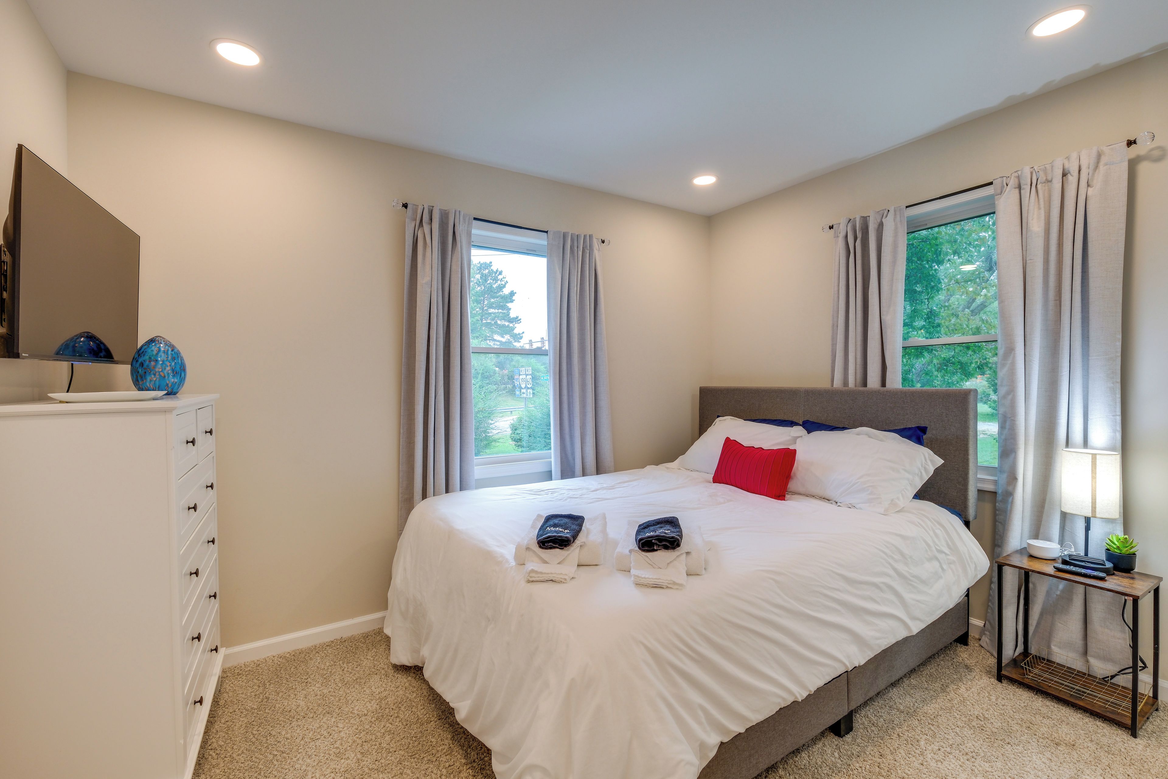 A hotel room with a bed, a nightstand, a lamp, and a dresser.