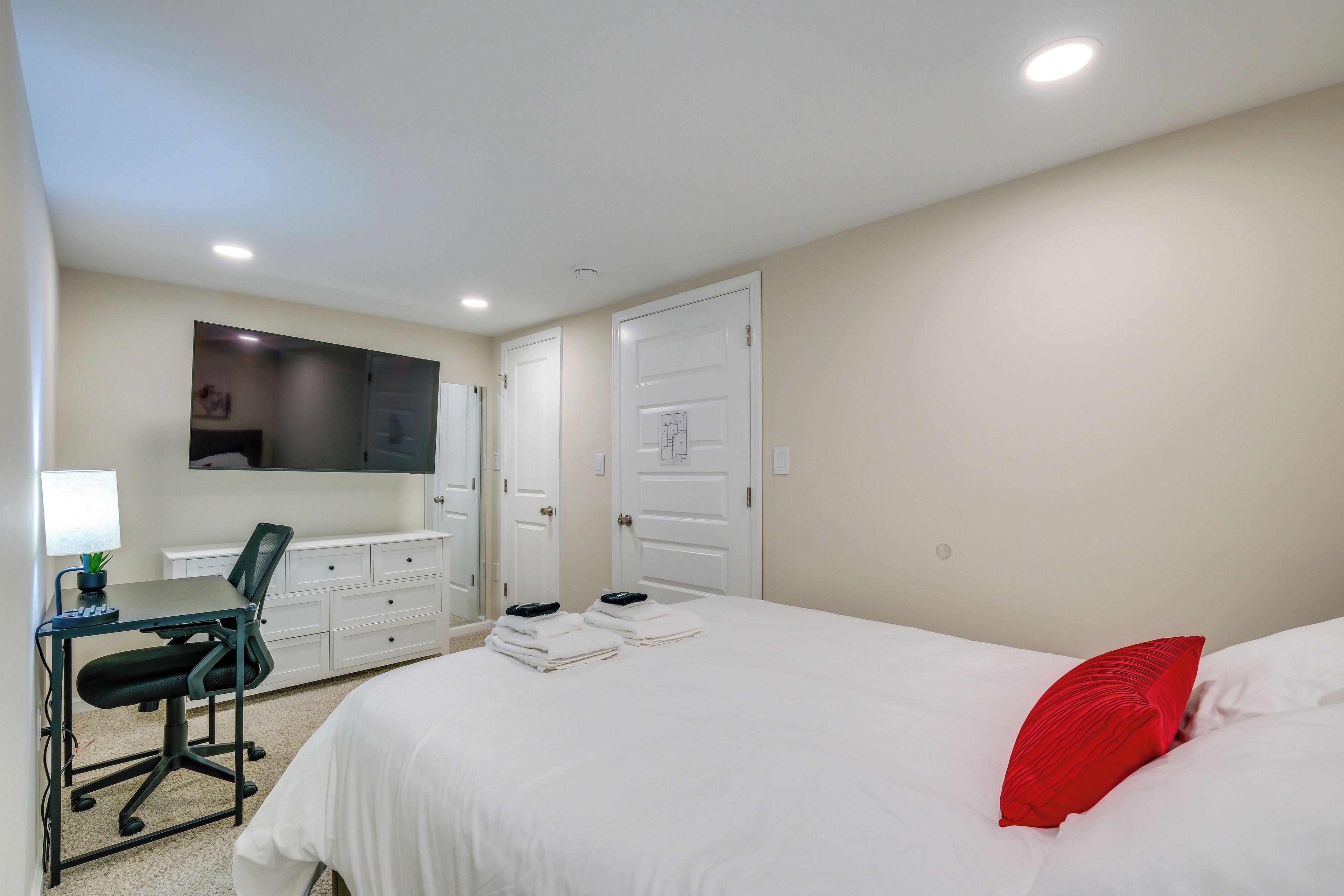 Een slaapkamer met een bed, een bureau, een stoel en een televisie aan de muur.
