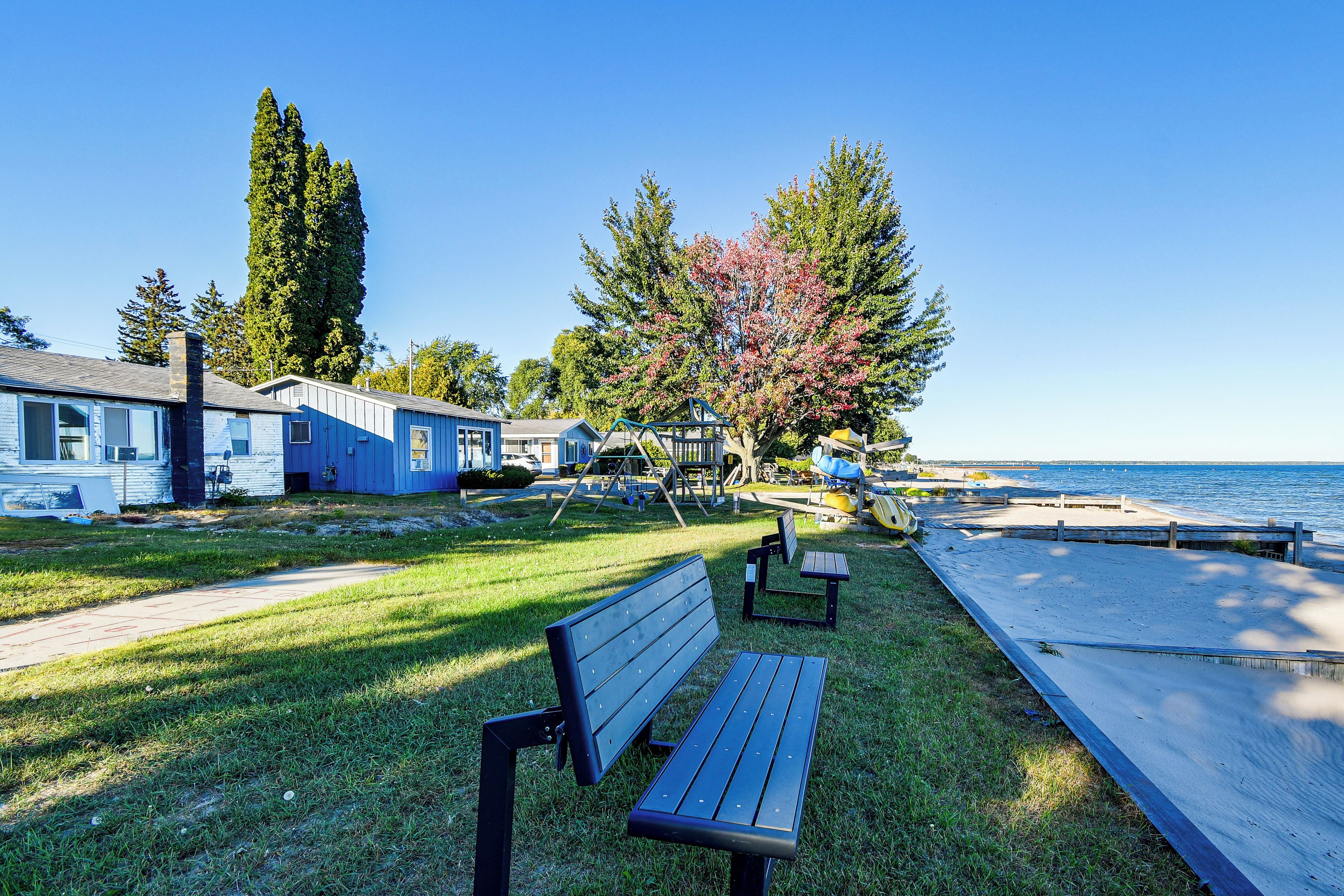 A waterfront park with a bench, playground, and a row of blue buildings.