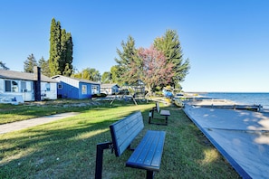 A waterfront park with a bench, playground, and a row of blue buildings. - Yard w/ Lake Views! Quaint Tawas City Escape (Tawas City)