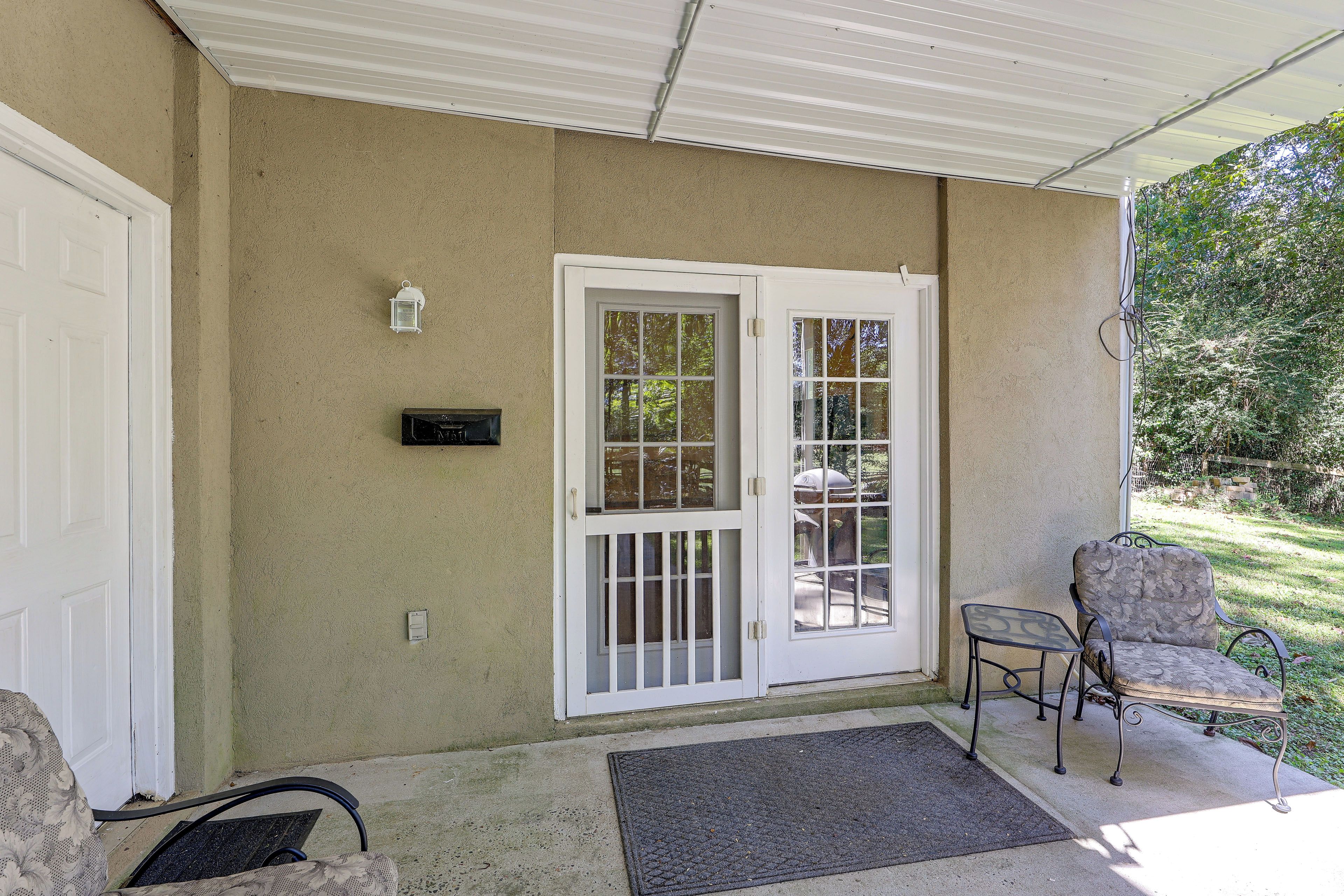 A covered porch with a white door, a small table, and a chair.