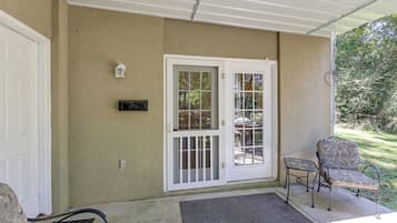 A covered porch with a white door, a small table, and a chair.
