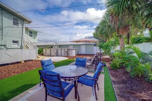 A backyard with a patio table and chairs, surrounded by a well-maintained lawn and various plants. - Cape Canaveral Getaway w/ Pool - Walk to Beach (Cape Canaveral)