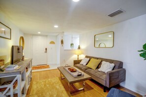 A living room with a sofa, coffee table, and a television. - Walk to the Beach! Bright Cape Canaveral Apt (Cape Canaveral)