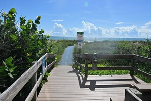 A wooden boardwalk leading to a beach with a sign indicating a sea turtle nesting area. - Walk to the Beach! Bright Cape Canaveral Apt (Cape Canaveral)