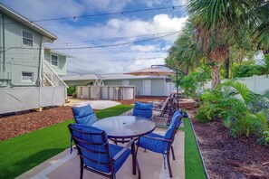A backyard with a patio table and chairs, surrounded by a lawn and a wooden deck. - Walk to the Beach! Bright Cape Canaveral Apt (Cape Canaveral)