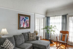 A living room with a grey sofa, a wooden rocking chair, a globe, and a framed painting on the wall. - Jastro Park-facing 1922 Condo in Bakersfield (Bakersfield)
