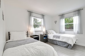 Een slaapkamer met twee bedden, een nachtkastje en een dressoir.