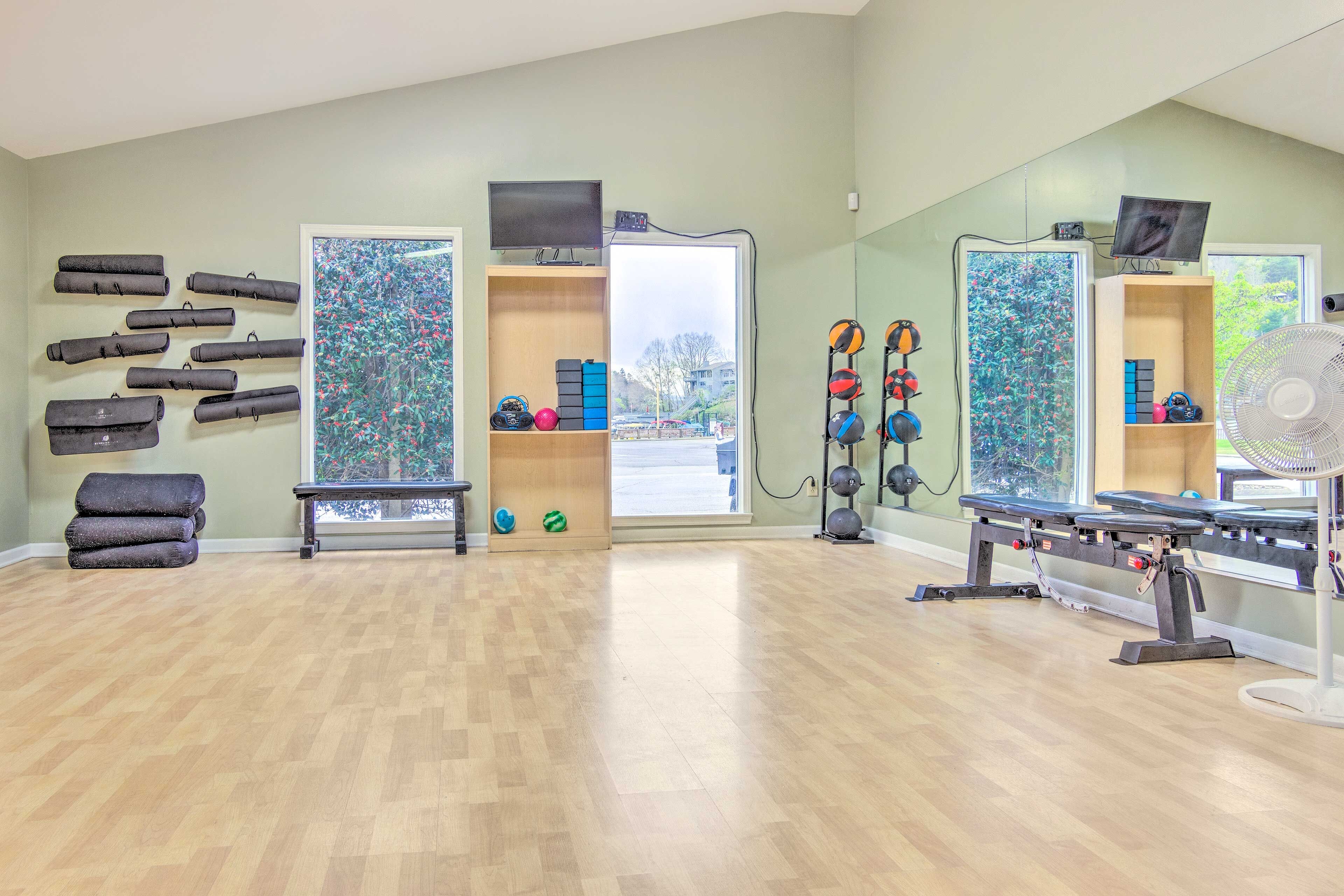 A gym with exercise equipment, a bench, and a wall-mounted TV.