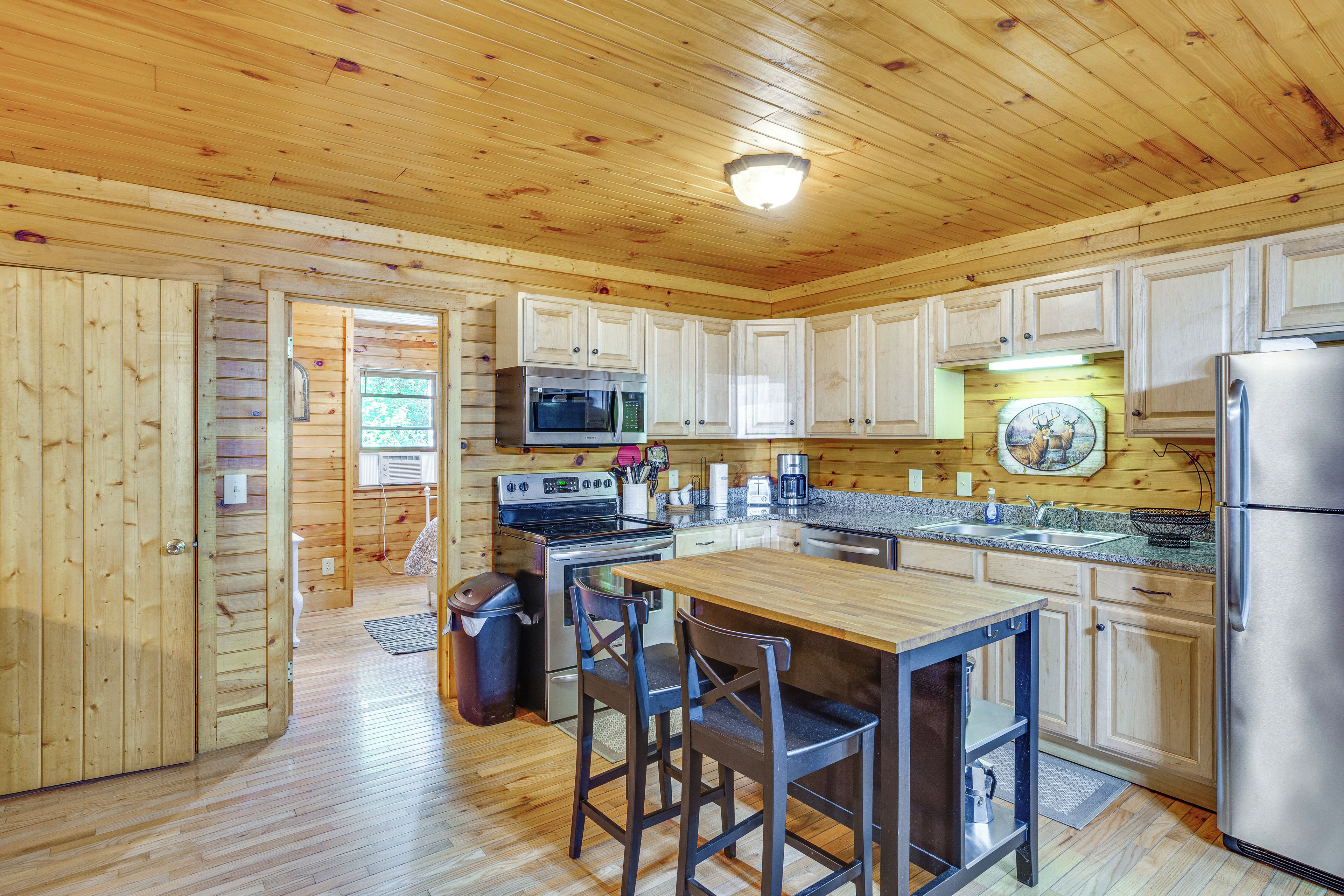 A compact kitchen with wooden cabinets, a stainless steel refrigerator, a microwave, and a stove.