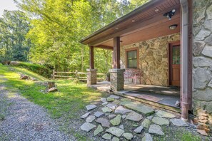 A stone building with a covered porch, a stone door, and a stone wall. - Rustic Cabin Retreat in the Peaceful Mountains (Elk Park)