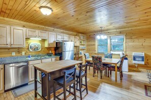 A wooden cabin interior with a kitchen, dining area, and a large window. - Rustic Cabin Retreat in the Peaceful Mountains (Elk Park)
