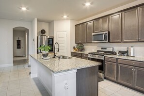 A modern kitchen with granite countertops, stainless steel appliances, and dark wooden cabinets. - Yard, Patio, Office! Spacious Home in Union Park (Aubrey)