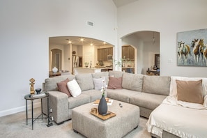 A spacious living room with a large sectional sofa, a coffee table, and a side table with decorative items. - Yard, Patio, Office! Spacious Home in Union Park (Aubrey)