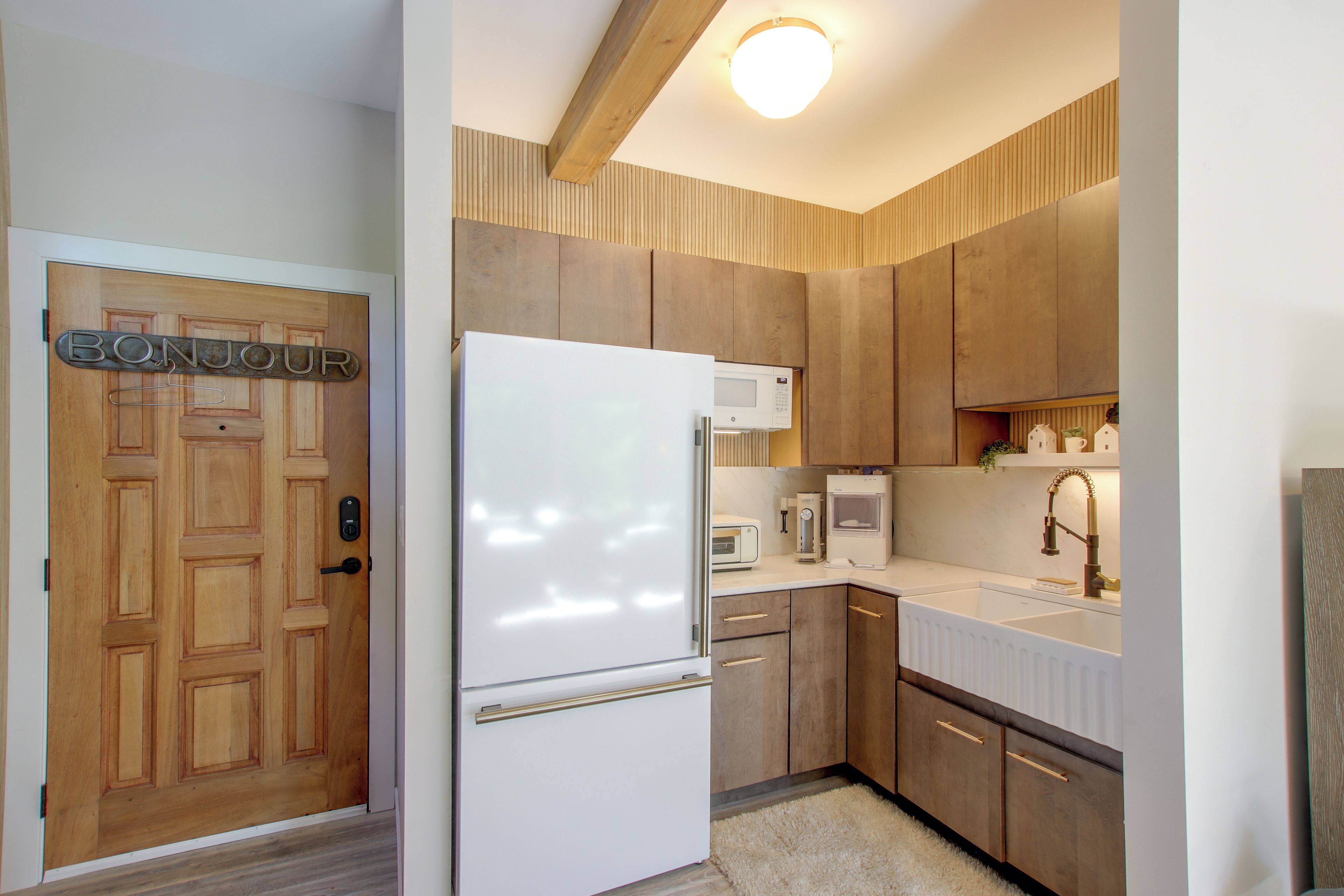 A modern kitchen with wooden cabinets, a white refrigerator, a microwave, and a coffee maker.