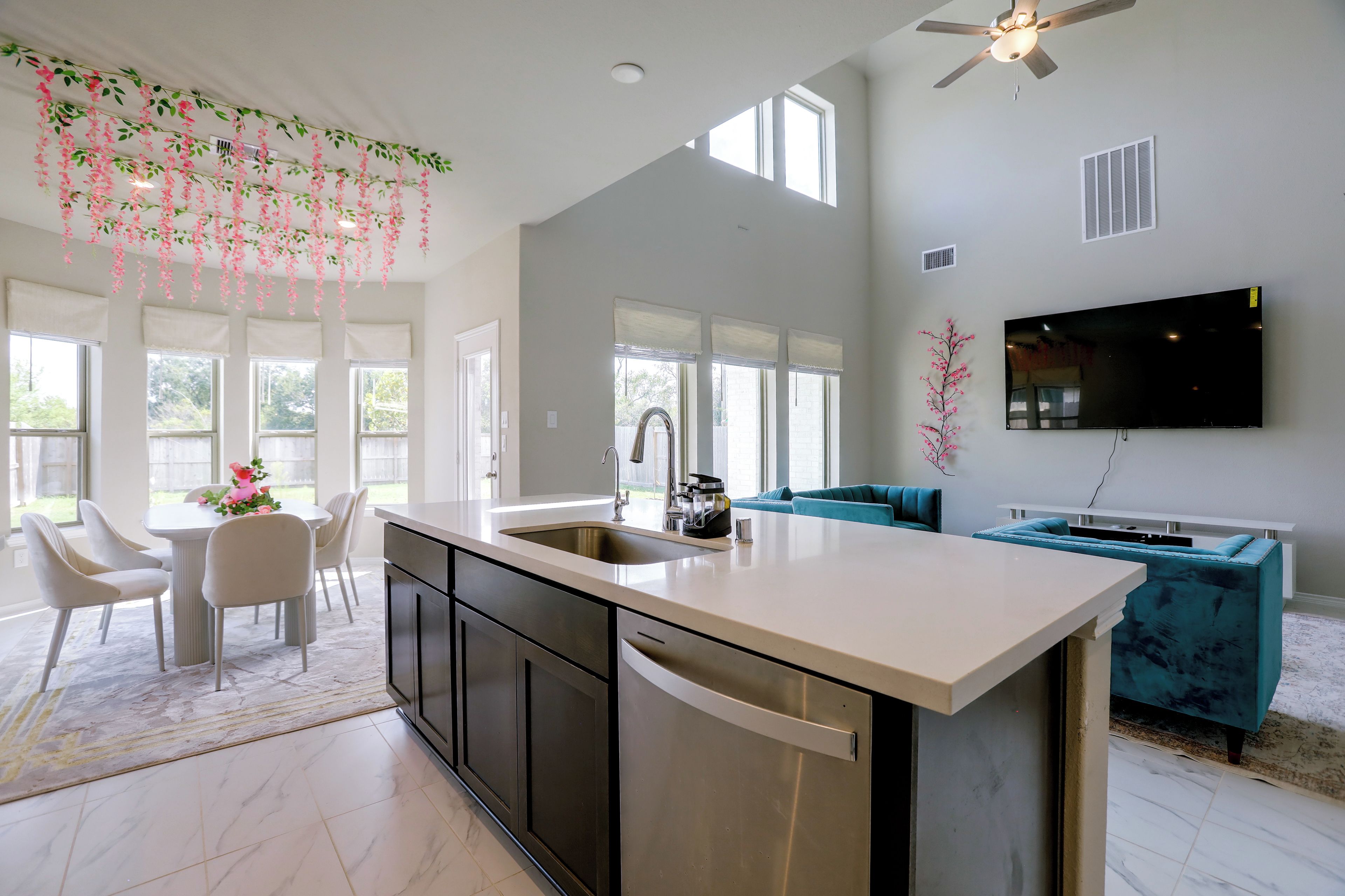 A modern kitchen with a central island, a dining area with chairs, and a living room with a sofa.