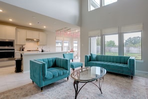 A spacious living area with teal sofas, a glass coffee table, and a kitchen in the background. - Richmond Home 12 Mi to Cinco Ranch Lakes (Richmond)