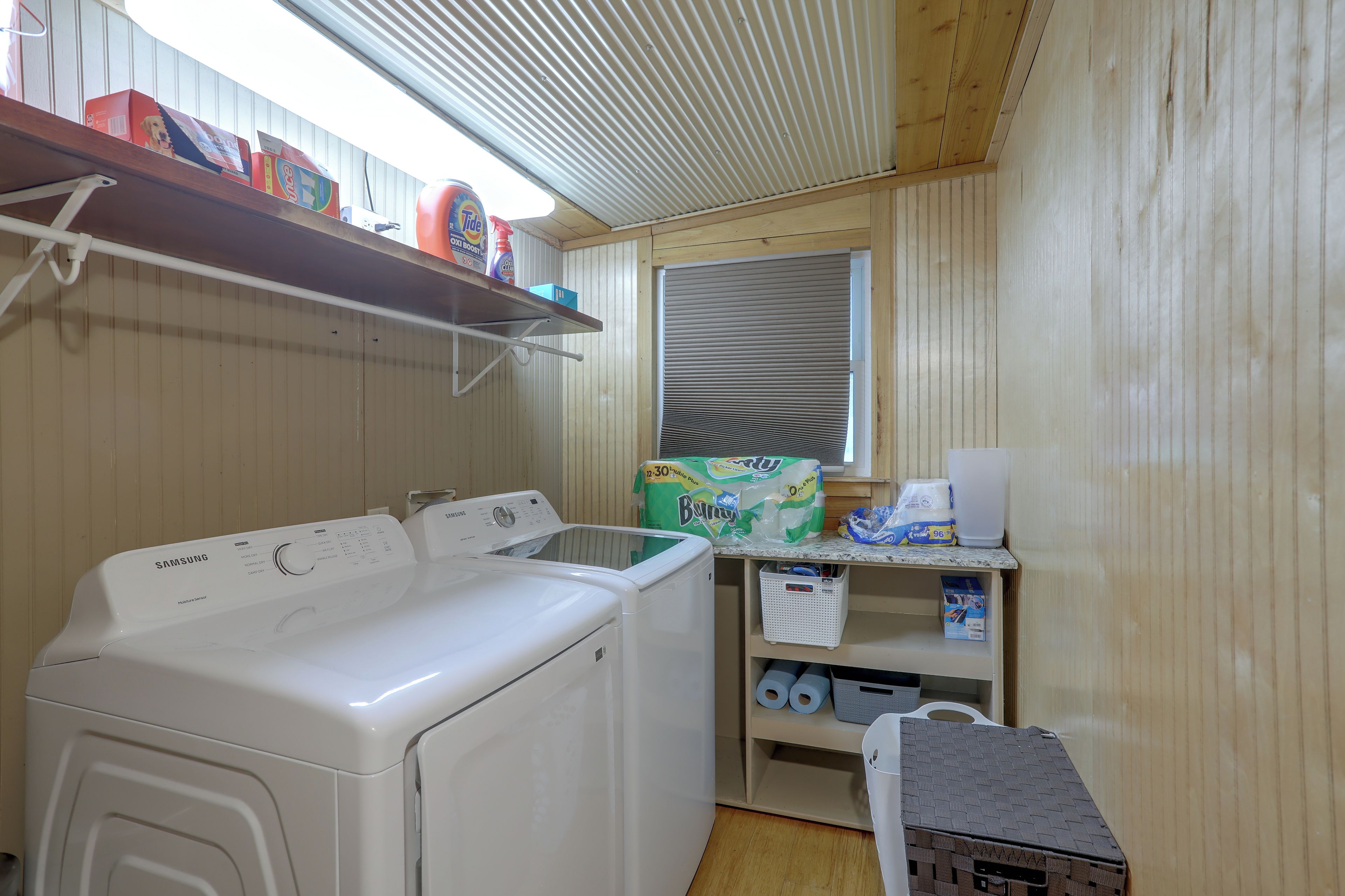 A laundry area with a Samsung dryer, a washing machine, and a shelf with cleaning supplies.