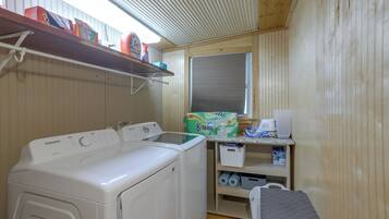 A laundry area with a Samsung dryer, a washing machine, and a shelf with cleaning supplies.