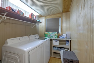 A laundry area with a Samsung dryer, a washing machine, and a shelf with cleaning supplies.