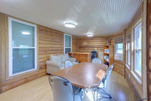 A cabin interior with a wooden dining table, two chairs, a sofa, and a small kitchenette area. - Bayou Days, Fire Pit Nights! Denham Springs Home (Denham Springs)