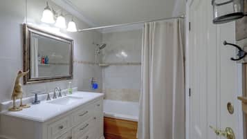 A bathroom with a double sink vanity, a shower with a handheld showerhead, and a bathtub.