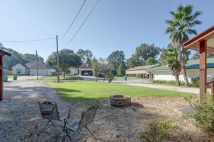 A residential area with a gravel driveway, a metal bench, a stone fire pit, and houses with green roofs.