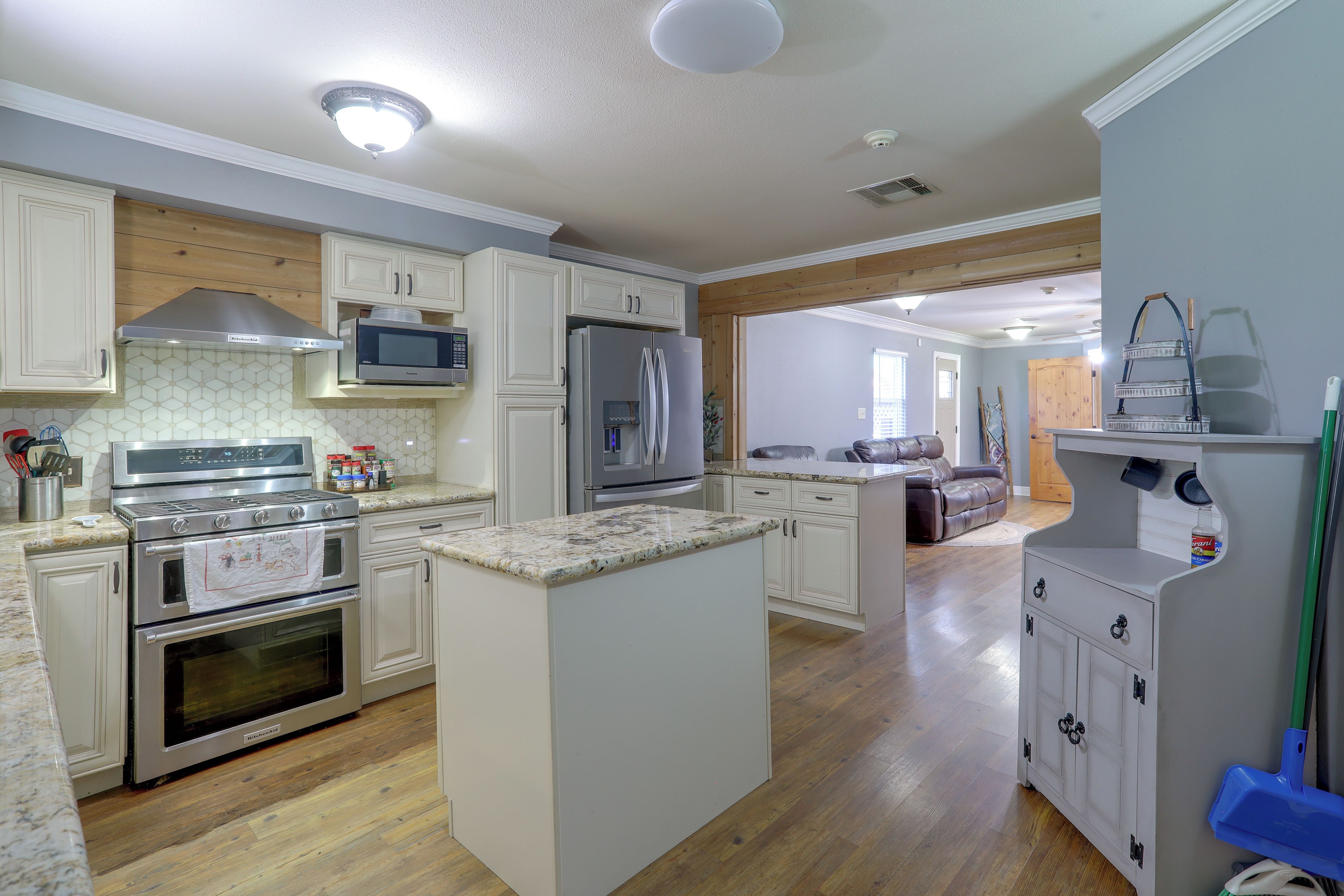 A modern kitchen with built-in appliances, wooden flooring, and a central island.