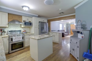 Una cocina moderna con electrodomésticos integrados, piso de madera e isla central.