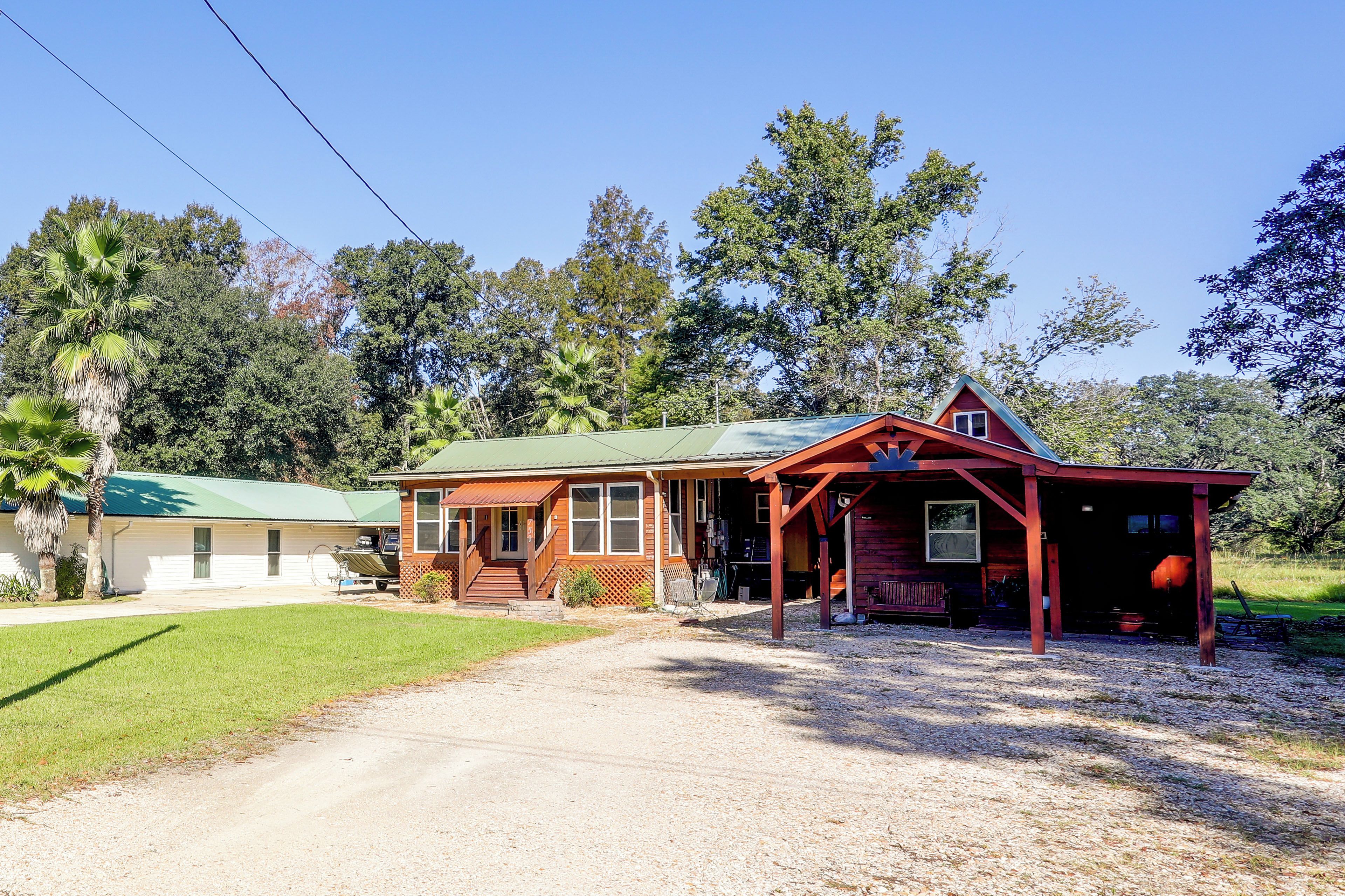 A two-story wooden house with a porch, a garage, and a gravel driveway.